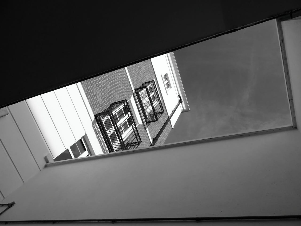 Dramatic black and white view of building facades with balconies from a unique low angle perspective.